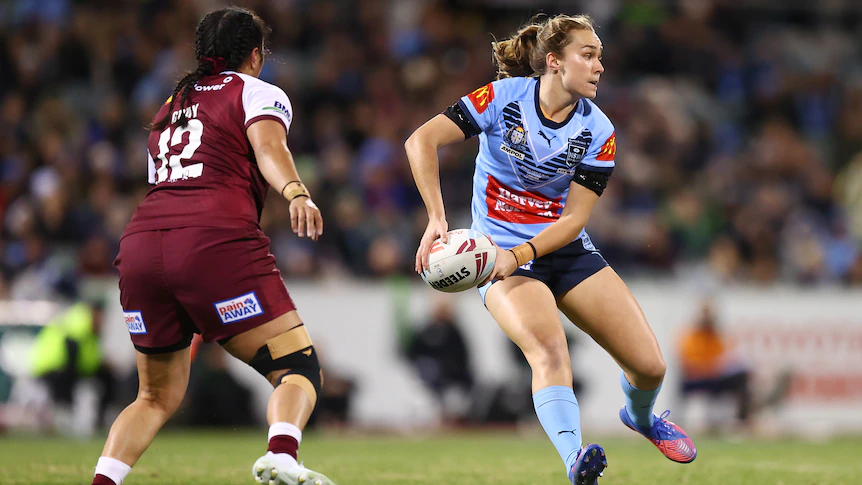 NSW Sky Blues' Kirra Dibb shapes to pass as she approaches a Queensland Maroons defender during the Women's State of Origin.