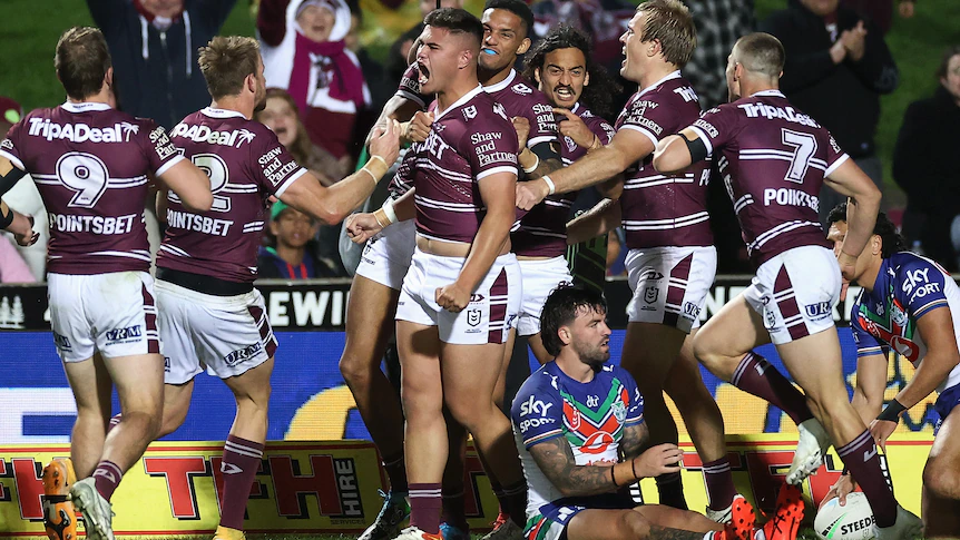 A group of Manly players celebrate together