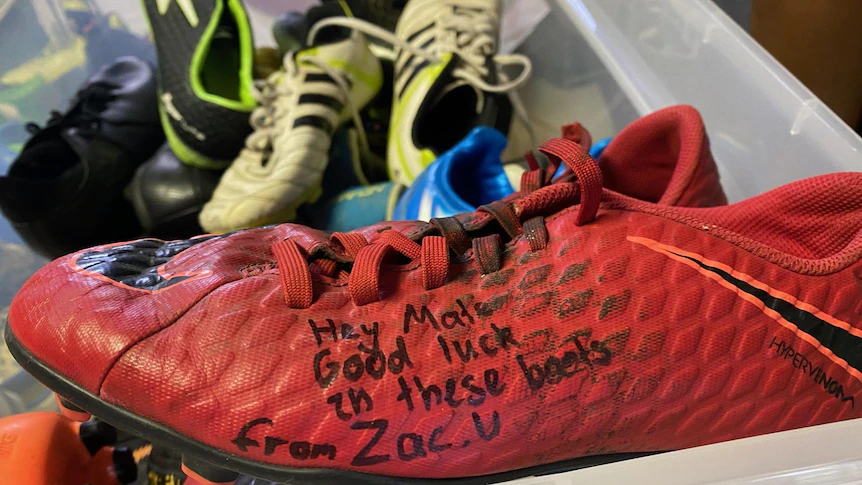 A red football boot with the message, Hey Mate, good luck in these boots from Zac.