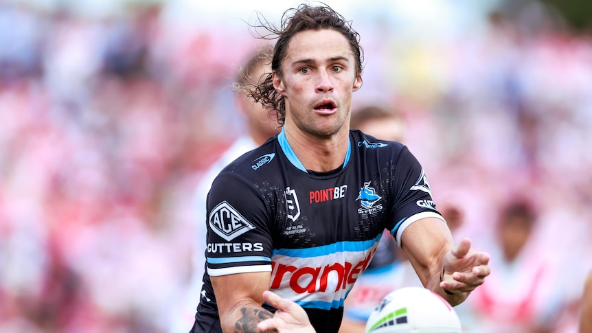 A Cronulla Sharks NRL player passes the ball to his right against St George Illawarra Drgaons.