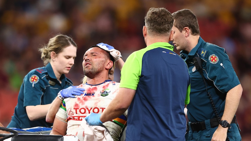 Jordan Rapana is carted off, leaning back with his eyes closed as paramedics hold his head