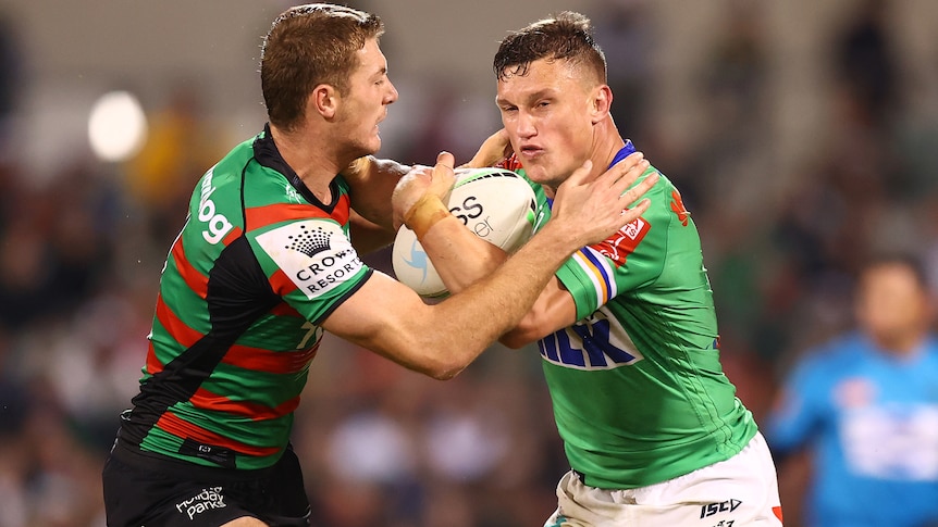 A man fends off a defender during a rugby league match