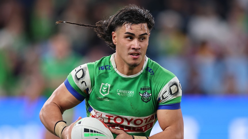 A man runs the ball during a rugby league match