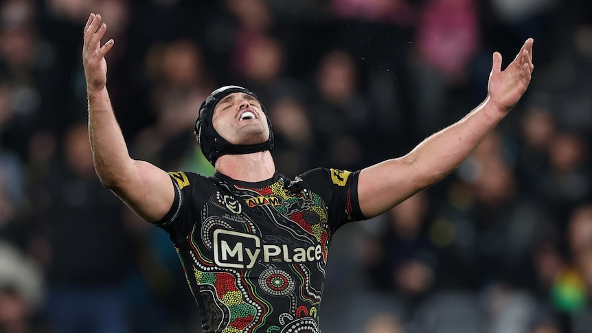 Nathan Cleary throws his head back and arms in the air during an NRL game.