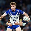 Lachlan Galvin of the Bulldogs is tackled, holding the football in one hand while standing